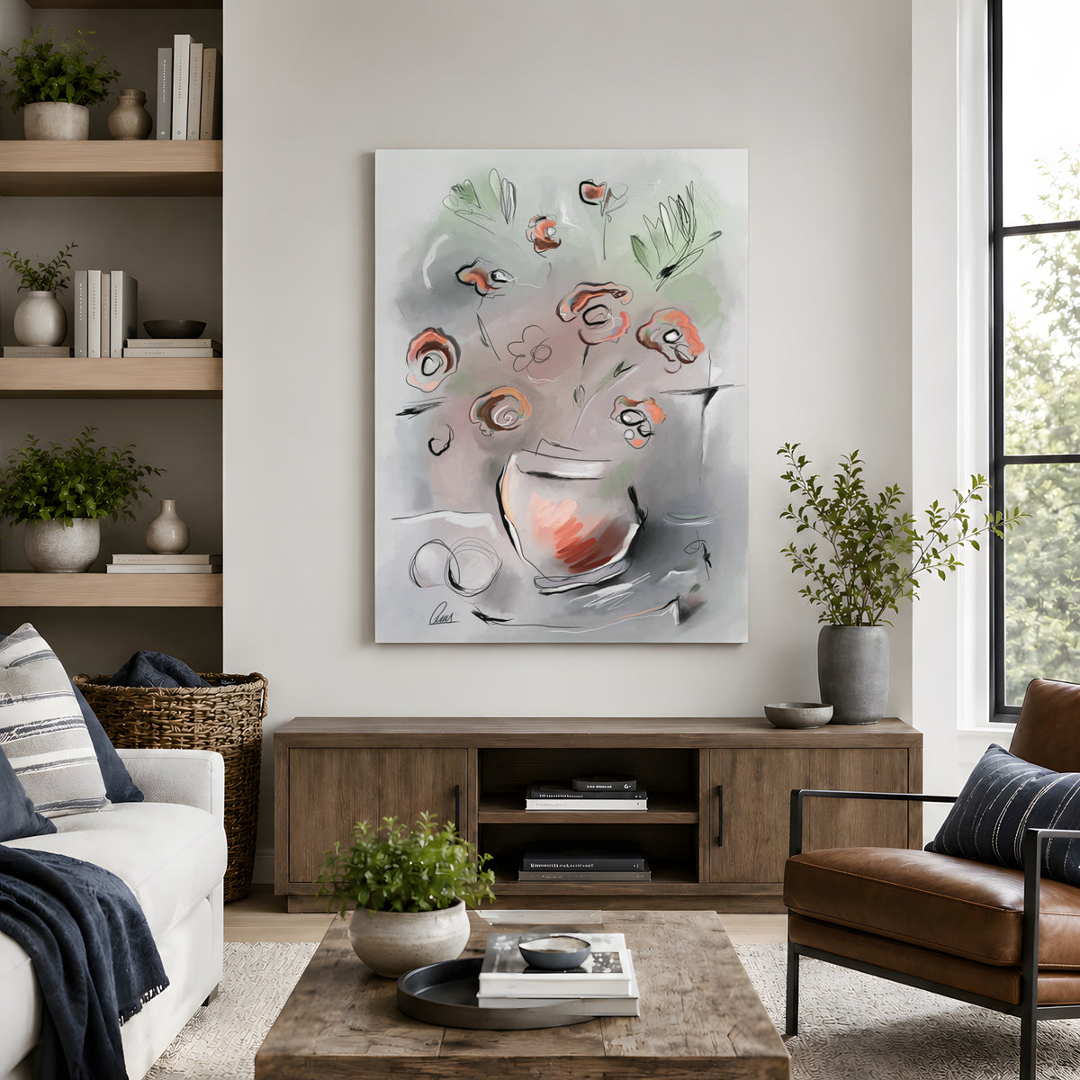 Abstract floral wall art hanging above a wooden console in a styled living room with a sofa, chair, plants, and window.