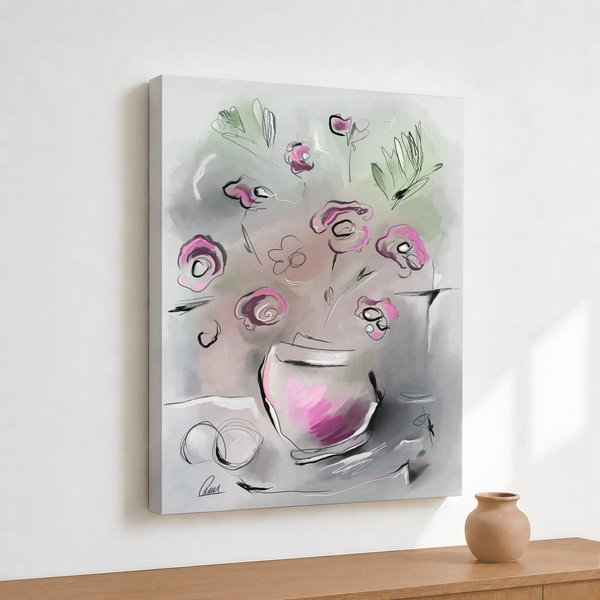 An abstract floral canvas print featuring pink flowers and green leaves in a gray and white watercolor style, displayed on a white wall above a wooden table with a small clay pot.